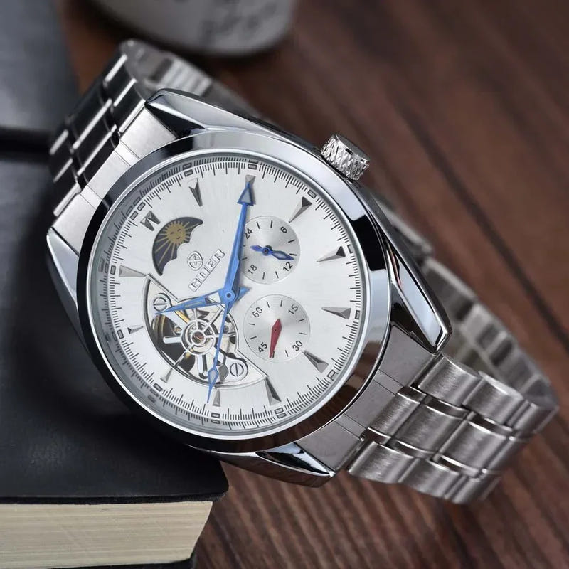 Men's mechanical hollow-dial watch, white face, blue hands, steel bracelet, angled
