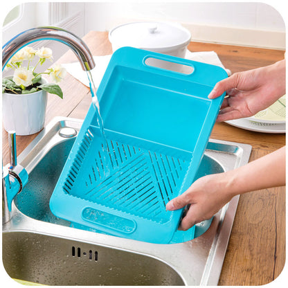 Person washing a blue cutting board and strainer in a kitchen sink.