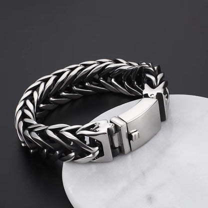 Silver braided bracelet on a dark surface with a marble base