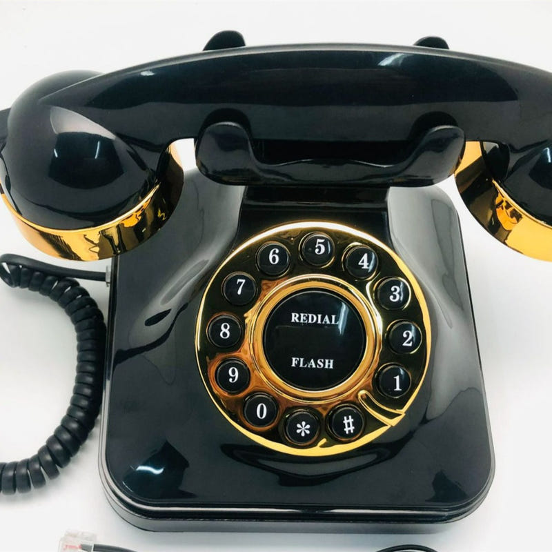 Black antique rotary telephone with gold dial and handset on top