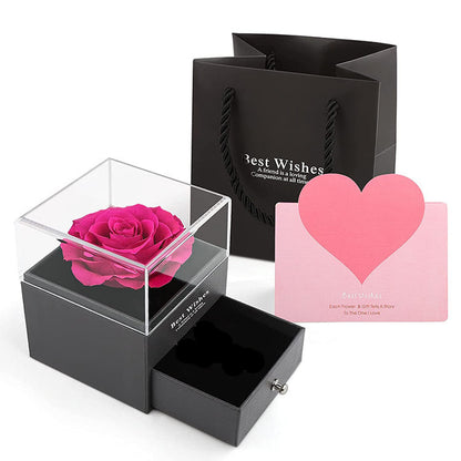 Black gift box with a pink rose, black gift bag, and pink card on a white background