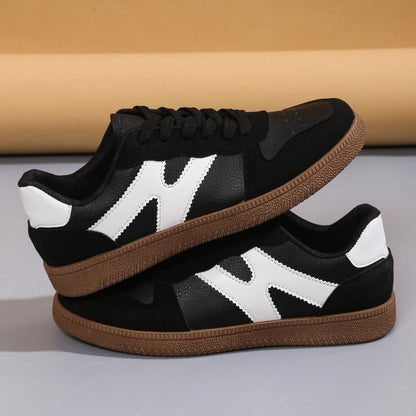 Women's low-top color-block sneakers, black with white panels and tan gum outsole.