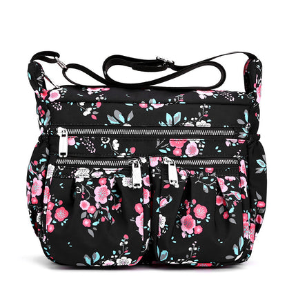 Large-capacity crossbody bag in black with pink floral print and front zip pockets.