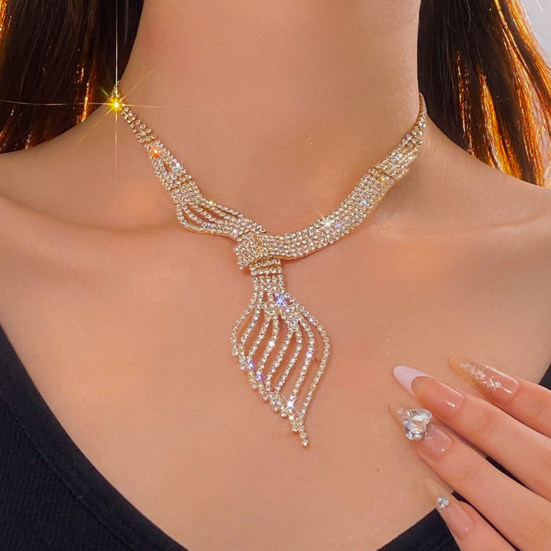 Gold-tone clavicle chain necklace with ribbon-like centerpiece and small hanging fringe