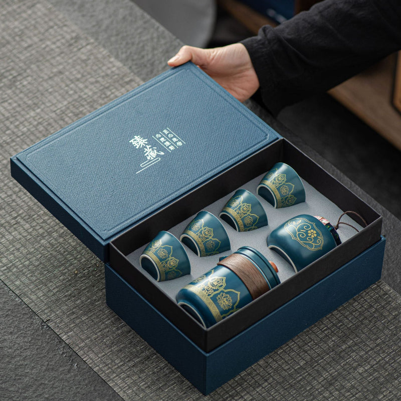 Set of blue ceramic cups with gold patterns in a decorative box on a textured surface.