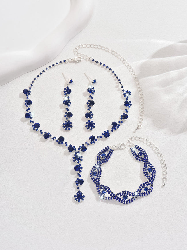 Blue beaded necklace, bracelet, and earrings on a white fabric background