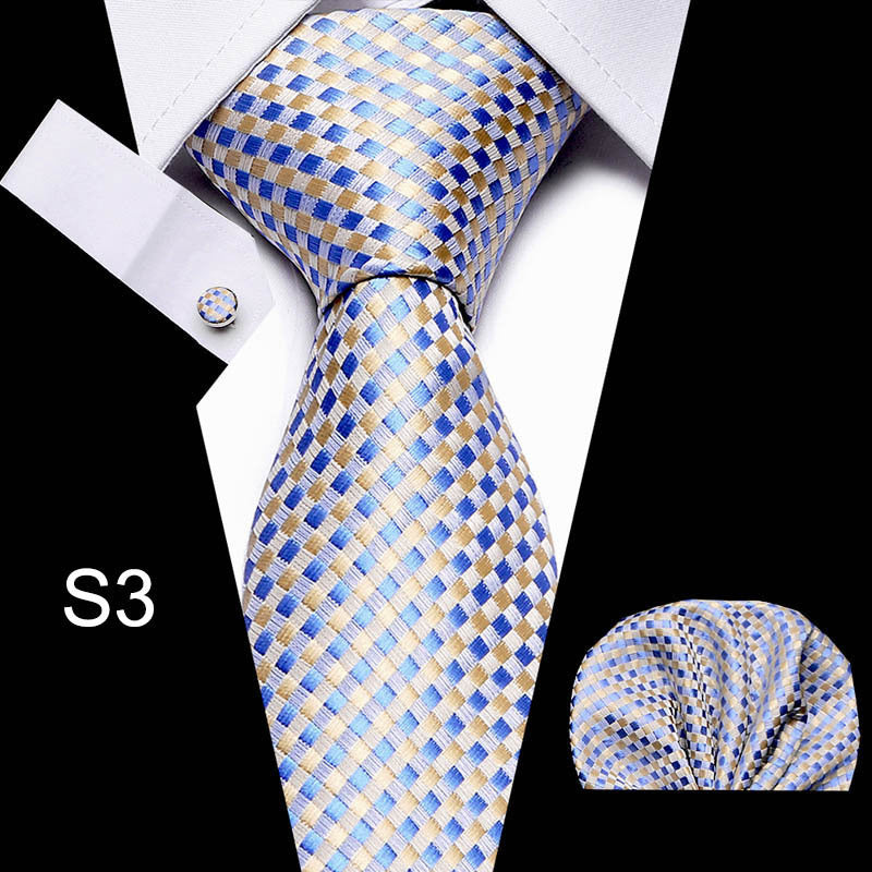 Blue and gold checkered tie with matching pocket square and cufflinks on a black background.