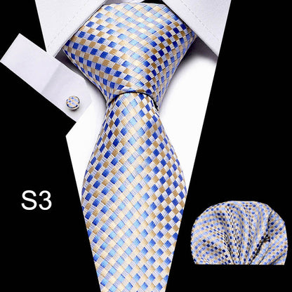 Blue and gold checkered tie with matching pocket square and cufflinks on a black background.