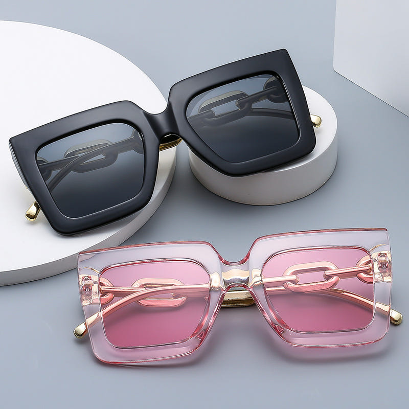 Square black sunglasses with gold chain detail and dark gray lenses