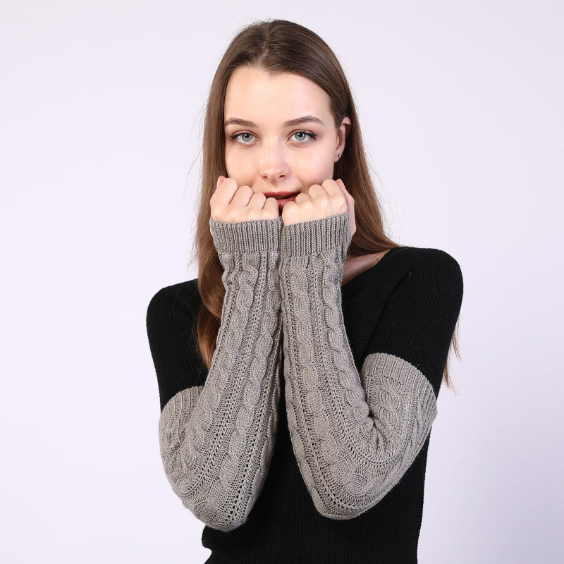 Person wearing gray cable knit arm warmers on a white background
