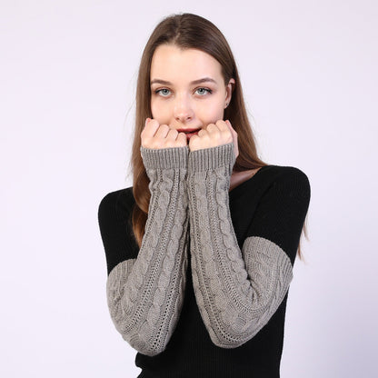 Person wearing gray cable knit arm warmers on a white background