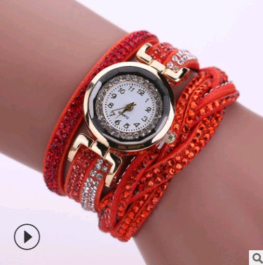 Red wristwatch with gemstone accents on a wrist against a white background