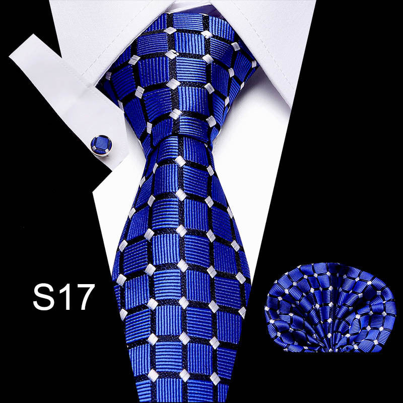 Blue patterned tie with matching pocket square and cufflinks on a white background