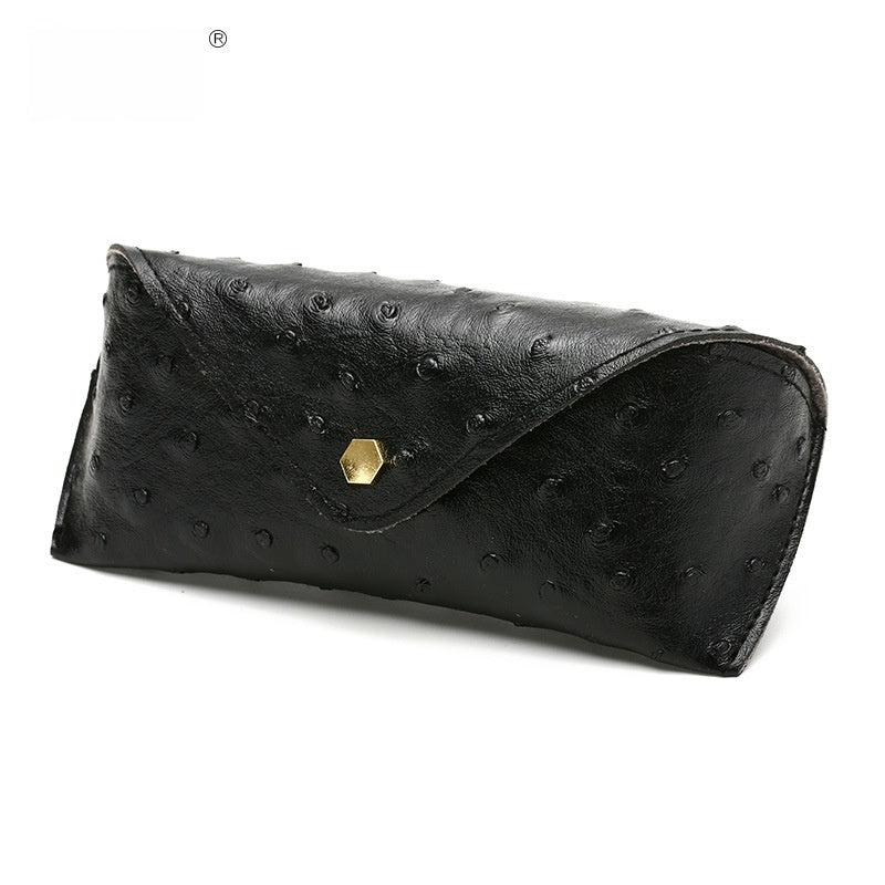 Black ostrich-patterned clutch bag with a gold hexagonal clasp on a white background