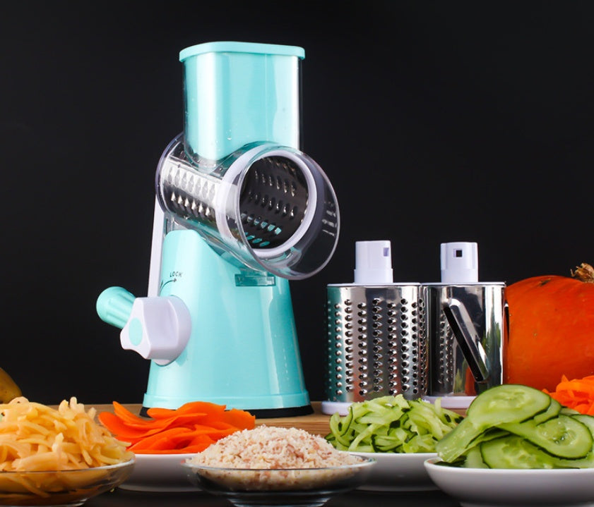 Turquoise manual vegetable grinder with sliced vegetables on a black background