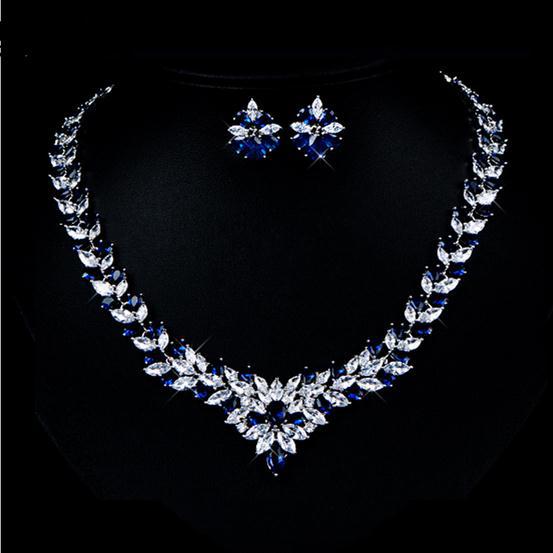Jewelry set with necklace and earrings featuring blue and clear stones on a black background