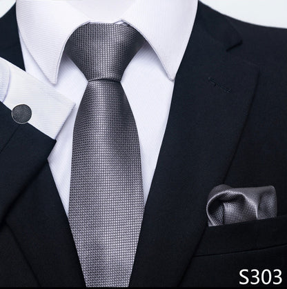 Gray patterned tie worn with a black suit and white shirt, with a matching pocket square.
