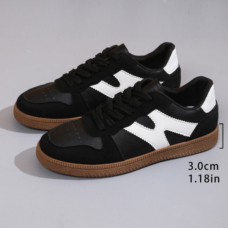Women's low-top color-block sneakers, black with white panels, lace-up and gum outsole.