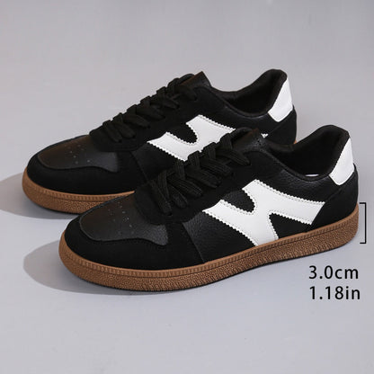 Women's low-top color-block sneakers, black with white panels, lace-up and gum outsole.