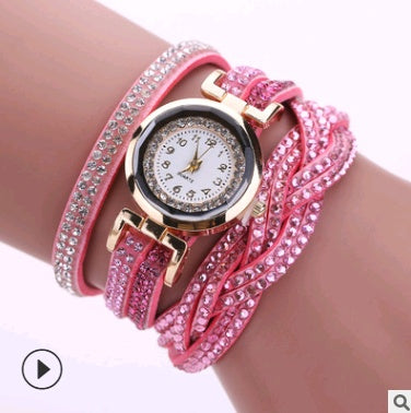 Pink wristwatch with rhinestone details on a white background
