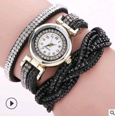Multistrand bracelet with a watch face on a wrist against a neutral background