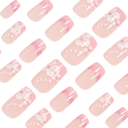 Set of pink press-on nails with French tips, glitter accents, and white bow/flower decals