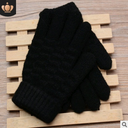 Pair of black knitted gloves on a wooden surface