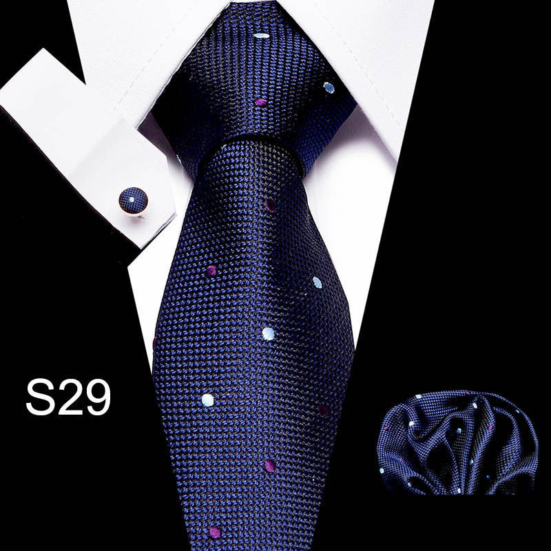 Navy blue patterned tie with matching pocket square and cufflinks on a white background