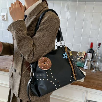 Person wearing a brown coat holding a black handbag with decorative elements in a kitchen setting.