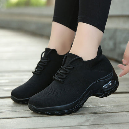 Black athletic shoes worn on a wooden floor