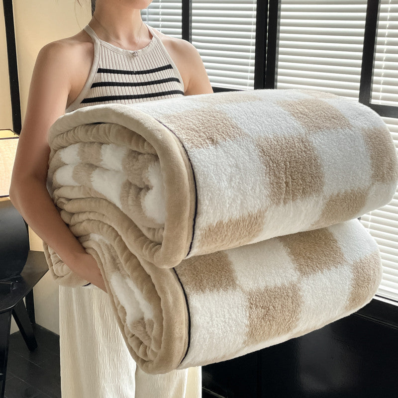 Person holding a folded checkered blanket in a room with blinds.