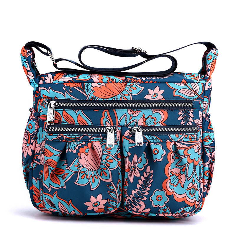 Large-capacity crossbody bag with bright multicolor floral print and front zip pockets.