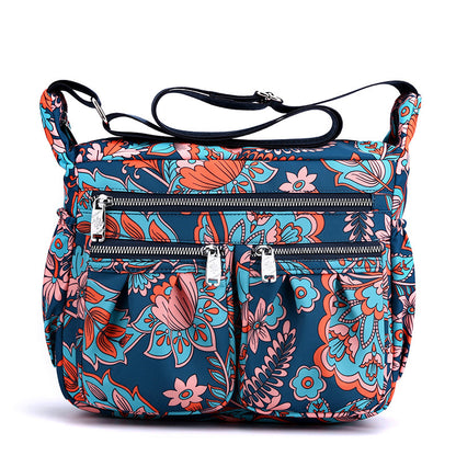 Large-capacity crossbody bag with bright multicolor floral print and front zip pockets.