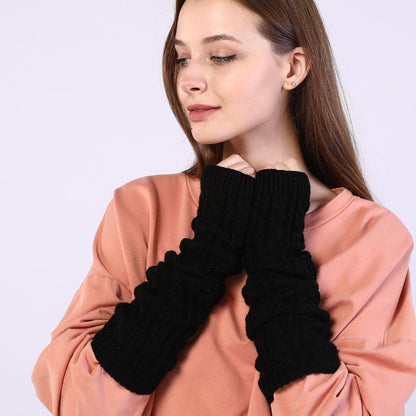 Woman wearing black ribbed arm warmers against a light purple background