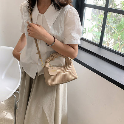 Person holding a beige handbag indoors near a window