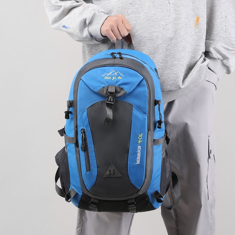 Blue and black backpack held by a person wearing a gray outfit on a light gray background