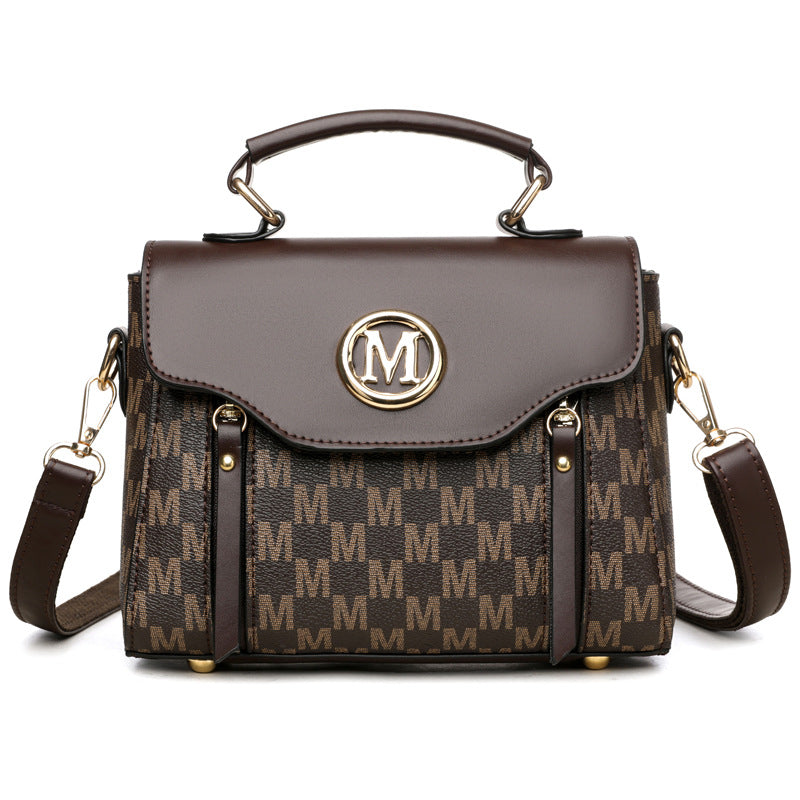 Brown handbag with gold accents and a prominent 'M' logo on a white background