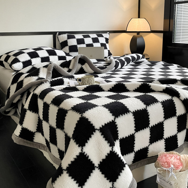 Bed with black and white checkered blanket and pillows in a bedroom setting.