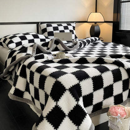 Bed with black and white checkered blanket and pillows in a bedroom setting.