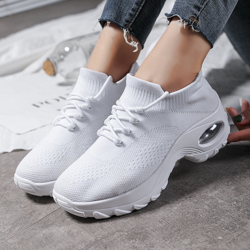 White sneakers worn with jeans on a gray floor.