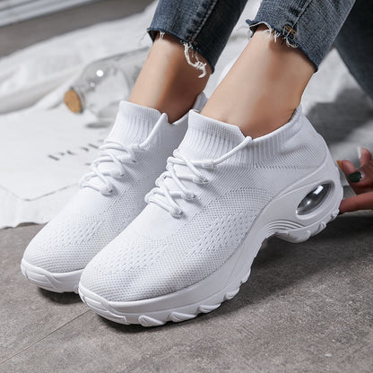 White sneakers worn with jeans on a gray floor.