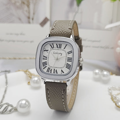 Watch with a gray strap and silver case on a white surface with pearls