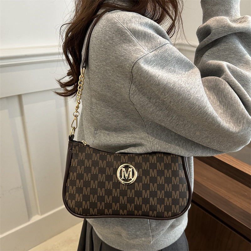 Women’s light brown monogram shoulder pouch bag worn crossbody with gold chain strap
