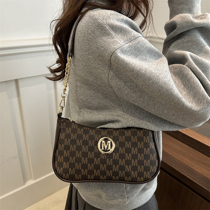 Women’s light brown monogram shoulder pouch bag worn crossbody with gold chain strap