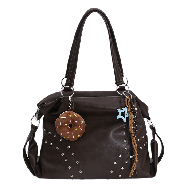 Brown handbag with decorative charms on a white background