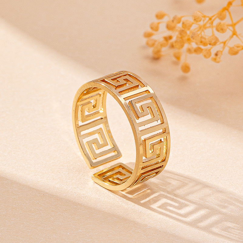 Gold ring with intricate design on a beige background