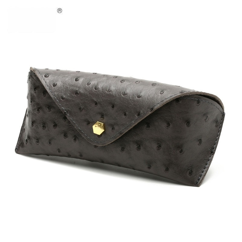 Black ostrich leather clutch bag with gold clasp on a white background