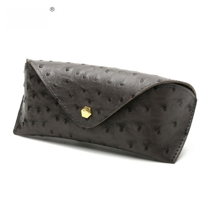 Black ostrich leather clutch bag with gold clasp on a white background