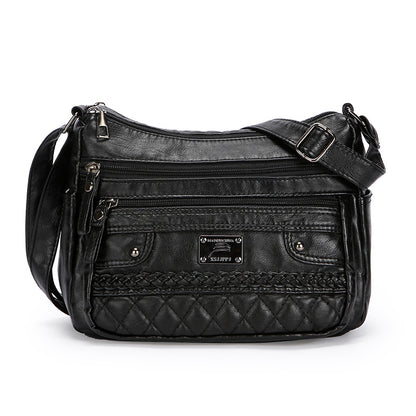 Black quilted handbag with multiple zippers on a white background