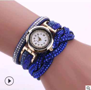 Blue beaded bracelet with a watch face on a wrist against a white background